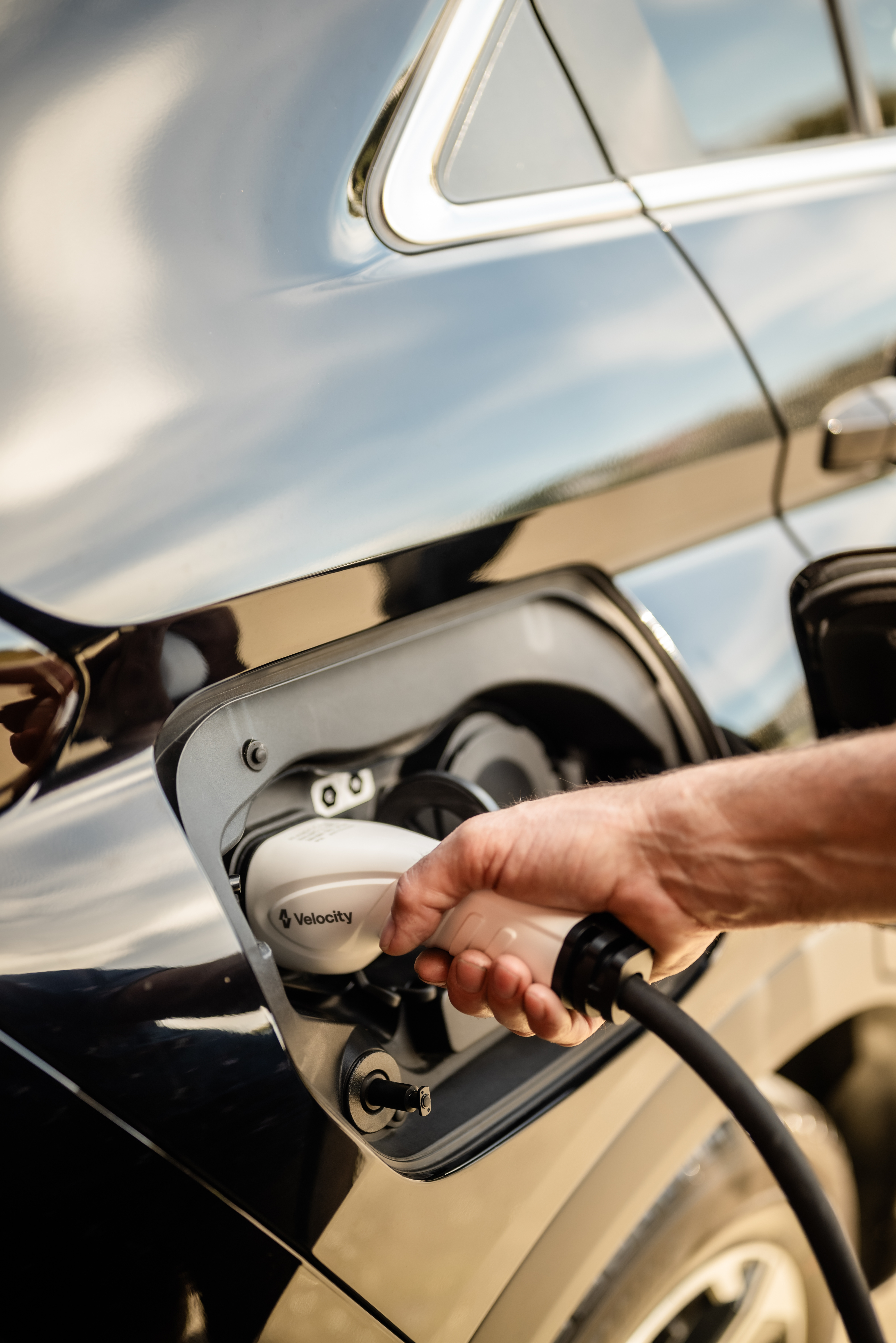 Hand placing Velocity charger into charging port of car